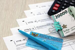 Annual Individual Income Tax Return forms with pen and indonesian rupiah bills photo
