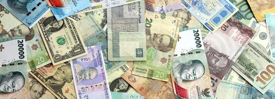 Many banknotes of different currency. Background of big amount of random money bills photo