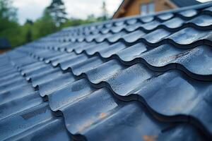 wet roof of modern house covered with black tiles against blue sky background close-up photo