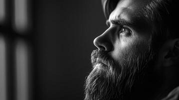 Moody black and white portrait of a bearded man, thoughtfully gazing into the distance photo
