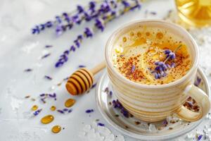 A cup of coffee with a spoon and a honey drizzle on top. The cup is on a white plate with lavender flowers photo