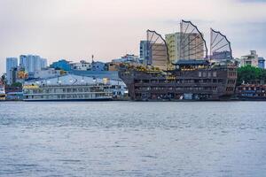Sunset view of Bitexco Tower, buildings, roads, Bason bridge and Saigon river in Ho Chi Minh city, container cargo ship on Saigon river. Travel concept. photo