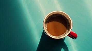 A red coffee cup with a brown liquid in it sits on a blue surface. The cup is half full, and the liquid appears to be a dark brown color. Concept of relaxation and comfort photo