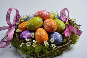 vistoso Pascua de Resurrección huevos arreglado en un decorativo nido con cinta acentos foto