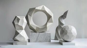 Three sculptures of different shapes and sizes are displayed on a white table. The sculptures are made of white marble and are placed on pedestals photo