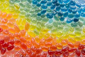 Rainbow-colored jellybeans arranged in a vibrant pattern on a transparent surface photo