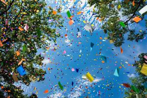 Rainbow-colored paper confetti falling transparently from the sky in celebration photo