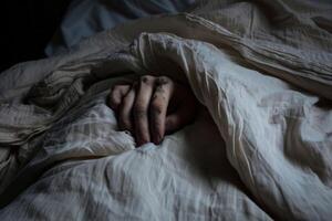 Close-up of a sleepless person's hand clutching the bedsheets in frustration photo