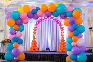 Colorful balloon arch framing a stage at a charity event, creating a festive backdrop photo