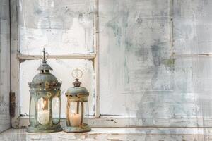 Two lanterns with candles inside sit on a window sill. The candles are lit, creating a warm and cozy atmosphere photo