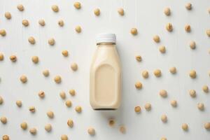 A bottle of milk is on a white background with many small white beans scattered around it photo