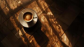 A coffee cup sits on a wooden table, with the sun shining on it photo
