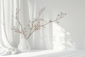 A white vase with a branch of flowers in it sits on a table. The vase is tall and narrow, and the flowers are small and delicate photo