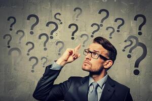 a man with perplexed facial expression and some question marks above his head. photo