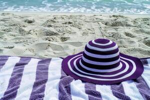 Purple and White Striped Hat on Beach Towel by the Seashore. summer vocation concept photo