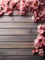 flat lay photo of sakura flowers cherry blossoms on bottom left and bottom right of a wooden background with copy space in the middle