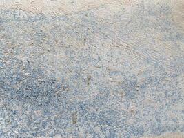 A white wall with a hole in it. The wall is cracked and has a rough texture photo