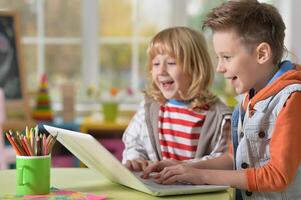 Two boys at class using laptop and writing photo