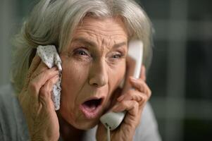 Portrait of sick senior woman talking on the phone photo