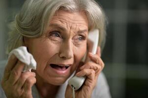 Portrait of sick senior woman talking on the phone photo