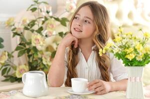 Smiling little girl holding big cup of tea photo
