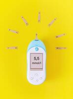 A blood glucose meter with test strips in the form of sunlight on a bright yellow background photo