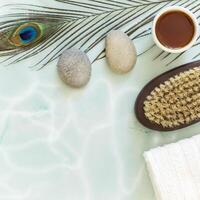 Flat lay composition with peacock feather, massage stones, oil, towel and body brush photo
