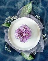 Spring composition with a white plate and flowers on a blue background photo