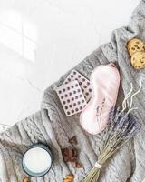 knitted blanket with a mask for sleep, pills, a bouquet of lavender, a glass of milk and sweet snack for good sleep photo