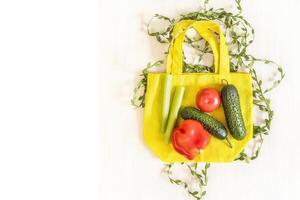 Cotton bag with seasonal vegetables for salad on white wooden background photo