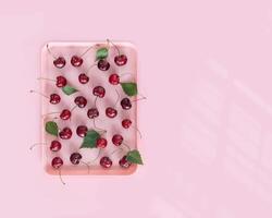 Pink, plastic tray with natural, farm, cherries on a pink background with copy space photo