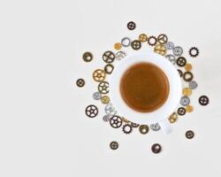 A cup of freshly brewed espresso around gears and cogs on a white background photo