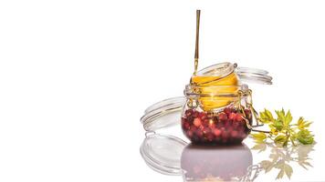 Isolated glass jars with honey-fermented cranberries and lemon on a white background photo