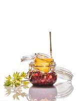 Isolated glass jars with honey-fermented cranberries and lemon on a white background photo