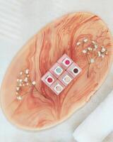 Jars of nail polish on a smalt pink stand and a white rolled-up towel on a textured, light table photo