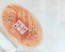 Jars of nail polish on a smalt pink stand and a white rolled-up towel on a textured table with copy space photo