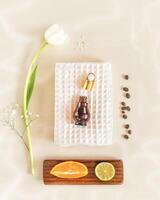 Eco friendly cosmetic composition with white towel, bottle of serum, orange, laim and tilip photo