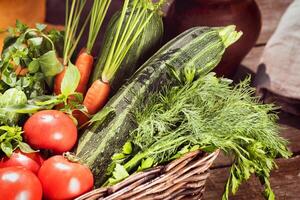 local, farm vegetables in a basket. tomatoes, cucumbers, zucchini, carrots, parsley, dill and basil photo