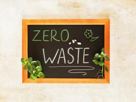 Composition with sprigs of domestic plants and a board with the chalk text zero waste photo