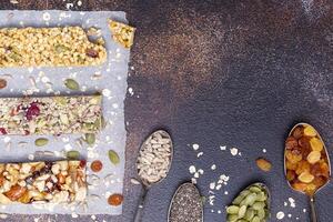 Granola cereal bars on a brown background with ingredients on spoons photo