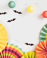 Helloween composition with colorful paper fans, helloween decorations and light garland on a blue background photo