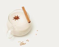 Glass cup of plant milk with a cinnamon stick and anise photo