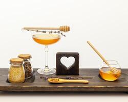 Bee products and honey in glass jars with honey dipper and lavender flowers on a wooden board photo