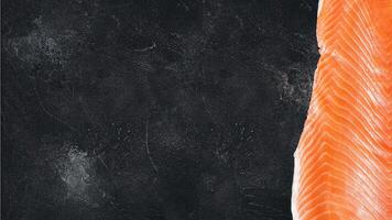 Raw salmon fillet on a black stone background with copy space photo