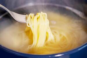 Spaghetti is cooked in boiling water in a saucepan photo