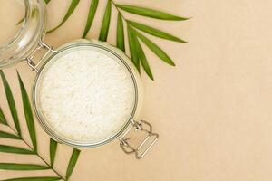 Rice grain in a glass bowl and palm leaves on a craft background photo