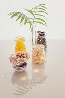 Different kind of vitamins in glass bottles, palm leaves and lighting garland on a light background photo