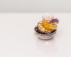 Different kind of capsuls in glass bowls with lighting garland on a white table with reflection photo