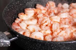 Pan with fried peeled shrimps spices and smoke photo