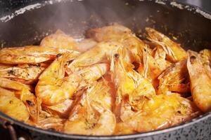 Pan of grilled prawn shrimps with garlic rosemary and spices with smoke photo